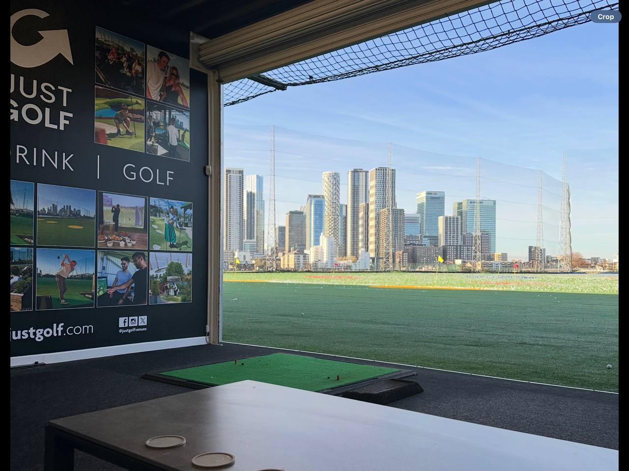 A bay at Greenwich Peninsula Golf Range, with the Canary Wharf skyline beyond the net